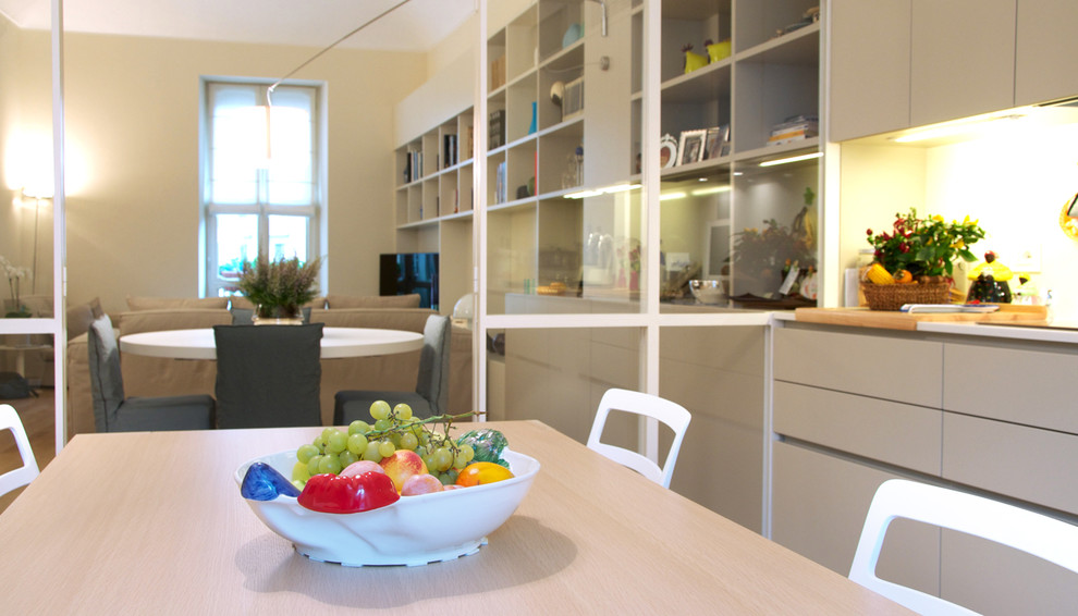 Foto di una cucina minimal con ante bianche, paraspruzzi bianco, parquet chiaro, nessuna isola e pavimento marrone