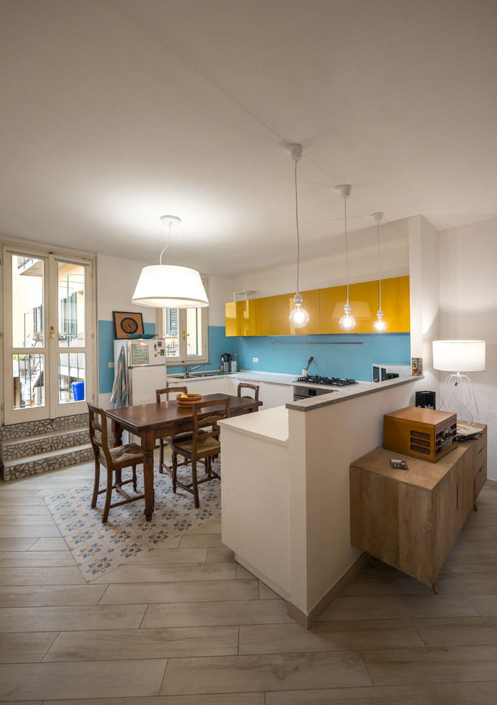 Свежая идея для дизайна: п-образная кухня-гостиная среднего размера в стиле фьюжн с двойной мойкой, плоскими фасадами, желтыми фасадами, столешницей из ламината, синим фартуком и белой техникой без острова - отличное фото интерьера
