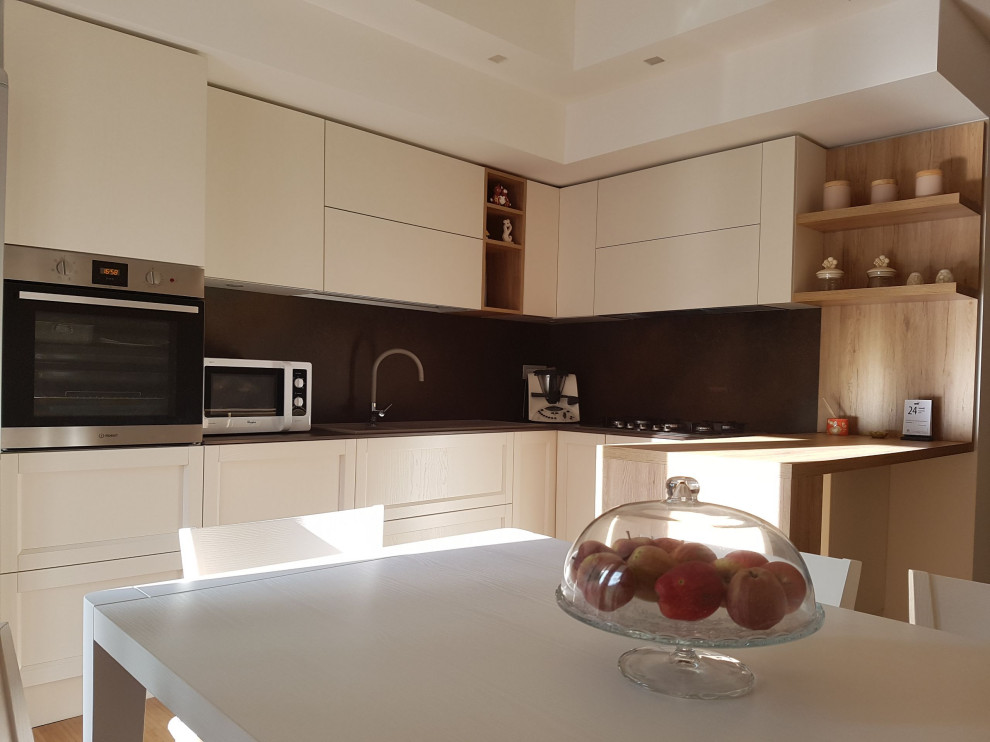 Small modern l-shaped enclosed kitchen in Other with a built-in sink, recessed-panel cabinets, light wood cabinets, composite countertops, stainless steel appliances and brown worktops.