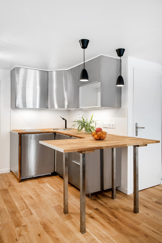 Inspiration for a small scandinavian u-shaped open plan kitchen in Paris with a built-in sink, flat-panel cabinets, stainless steel cabinets, wood worktops, integrated appliances, light hardwood flooring and no island.