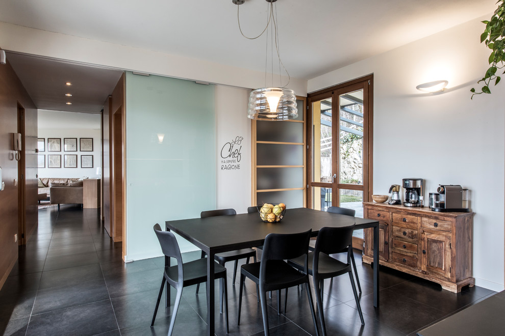 Large trendy slate floor and black floor kitchen/dining room combo photo in Milan