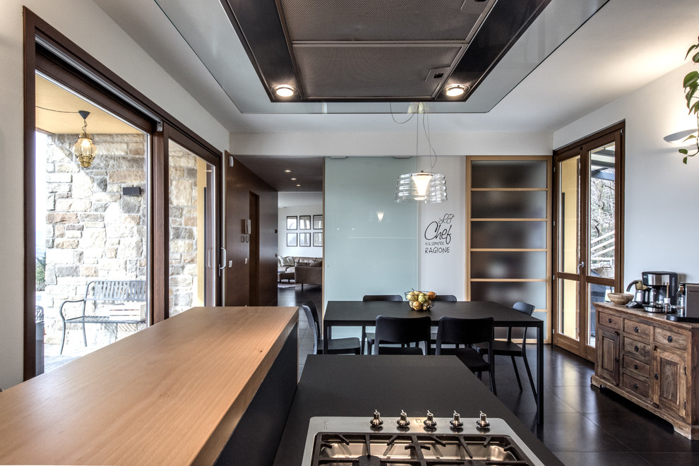 Idee per una grande sala da pranzo aperta verso la cucina minimal con pavimento in gres porcellanato e pavimento nero