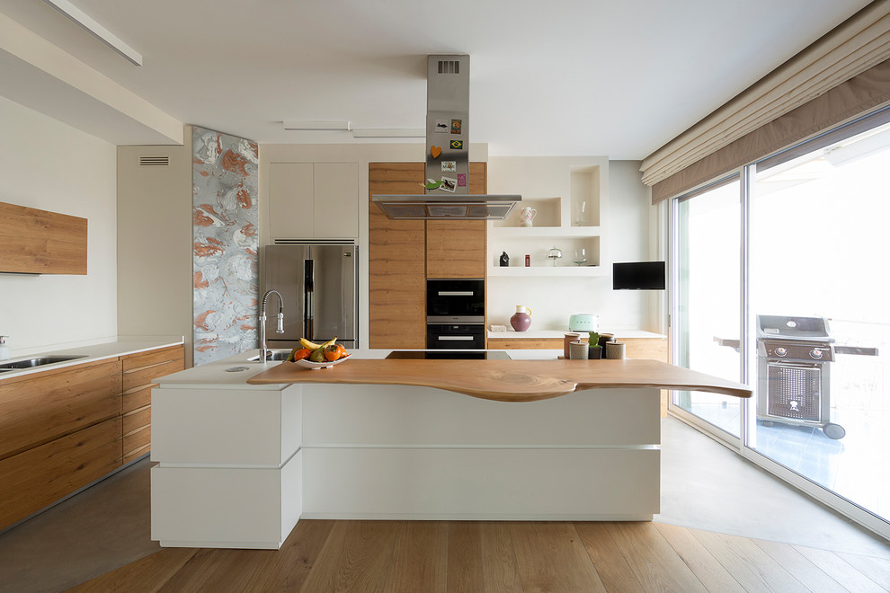 Modern inredning av ett avskilt, mellanstort vit vitt l-kök, med en undermonterad diskho, släta luckor, svarta vitvaror, betonggolv, en köksö, grått golv och skåp i mellenmörkt trä