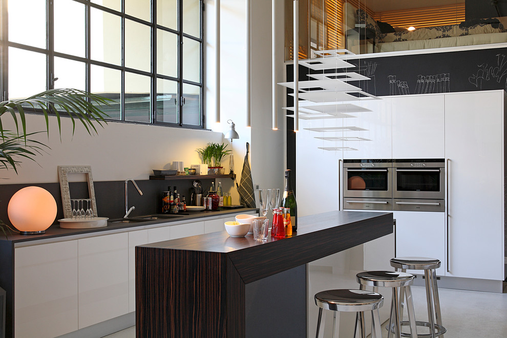 Idee per una cucina contemporanea con lavello sottopiano, ante lisce, ante bianche, top in legno, elettrodomestici in acciaio inossidabile e pavimento in cemento