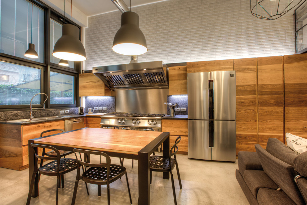 Foto di una grande cucina industriale con lavello a doppia vasca, ante lisce, ante in legno chiaro, top in granito, elettrodomestici in acciaio inossidabile e pavimento grigio