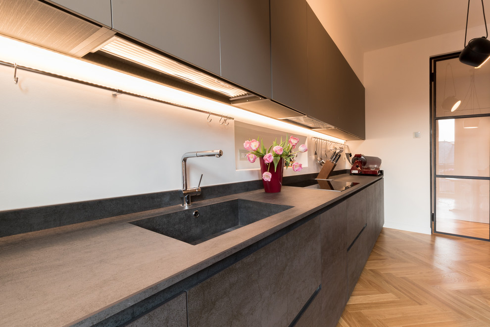 Photo of a medium sized contemporary galley enclosed kitchen in Milan with beaded cabinets, grey cabinets, an integrated sink, tile countertops, light hardwood flooring and brown floors.