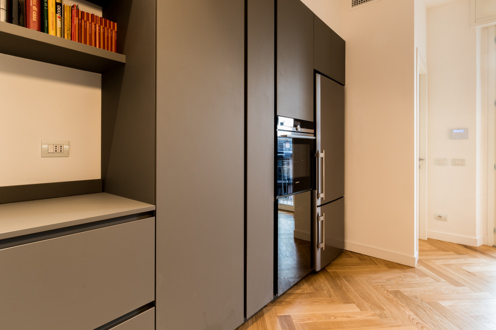 Imagen de cocina lineal contemporánea de tamaño medio cerrada con armarios con rebordes decorativos, puertas de armario grises, encimera de laminado, suelo de madera clara y suelo marrón