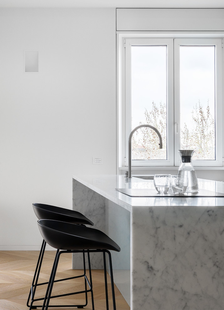 Exempel på ett stort modernt vit linjärt vitt kök med öppen planlösning, med en undermonterad diskho, släta luckor, vita skåp, marmorbänkskiva, grått stänkskydd, glaspanel som stänkskydd, rostfria vitvaror, mellanmörkt trägolv, en köksö och beiget golv