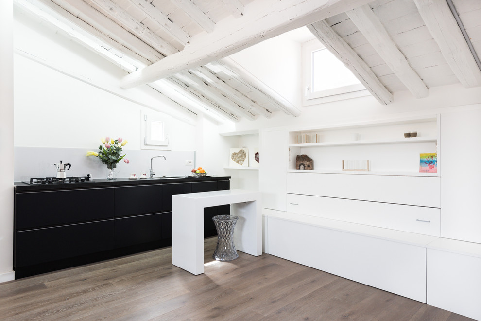 Foto di una piccola cucina design con lavello a doppia vasca, ante lisce, ante nere, paraspruzzi bianco, elettrodomestici da incasso e parquet chiaro