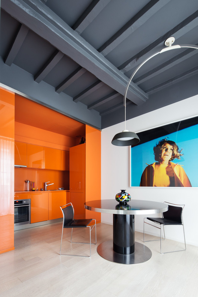 Источник вдохновения для домашнего уюта: прямая кухня среднего размера в современном стиле с обеденным столом, плоскими фасадами, оранжевыми фасадами, оранжевым фартуком и техникой из нержавеющей стали без острова