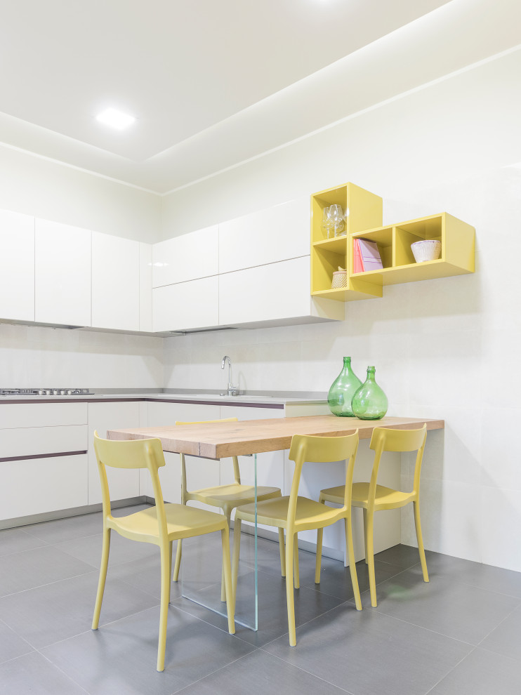 Immagine di una grande cucina minimalista con ante lisce, ante beige, top in superficie solida, pavimento in gres porcellanato, penisola, pavimento grigio e top beige