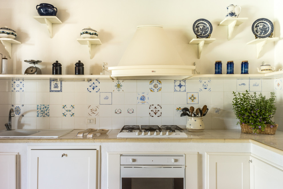Imagen de cocinas en L mediterránea con fregadero encastrado, armarios con paneles empotrados, puertas de armario blancas, salpicadero multicolor, electrodomésticos blancos y encimeras beige