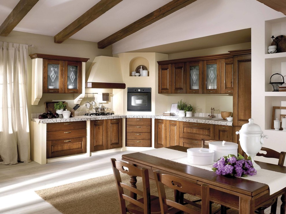 Example of a large tuscan l-shaped painted wood floor and white floor eat-in kitchen design in Catania-Palermo with a single-bowl sink, raised-panel cabinets, medium tone wood cabinets, tile countertops, white backsplash, mosaic tile backsplash and black appliances