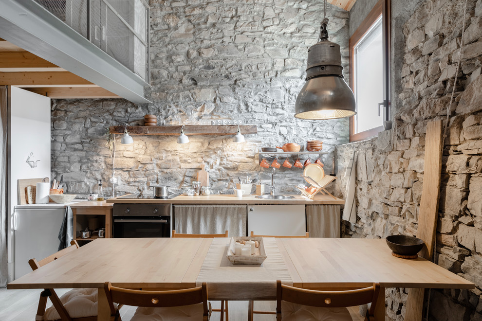 Diseño de cocina comedor lineal mediterránea sin isla con fregadero encastrado, armarios con paneles lisos, puertas de armario blancas, encimera de madera, encimeras beige y pared de piedra