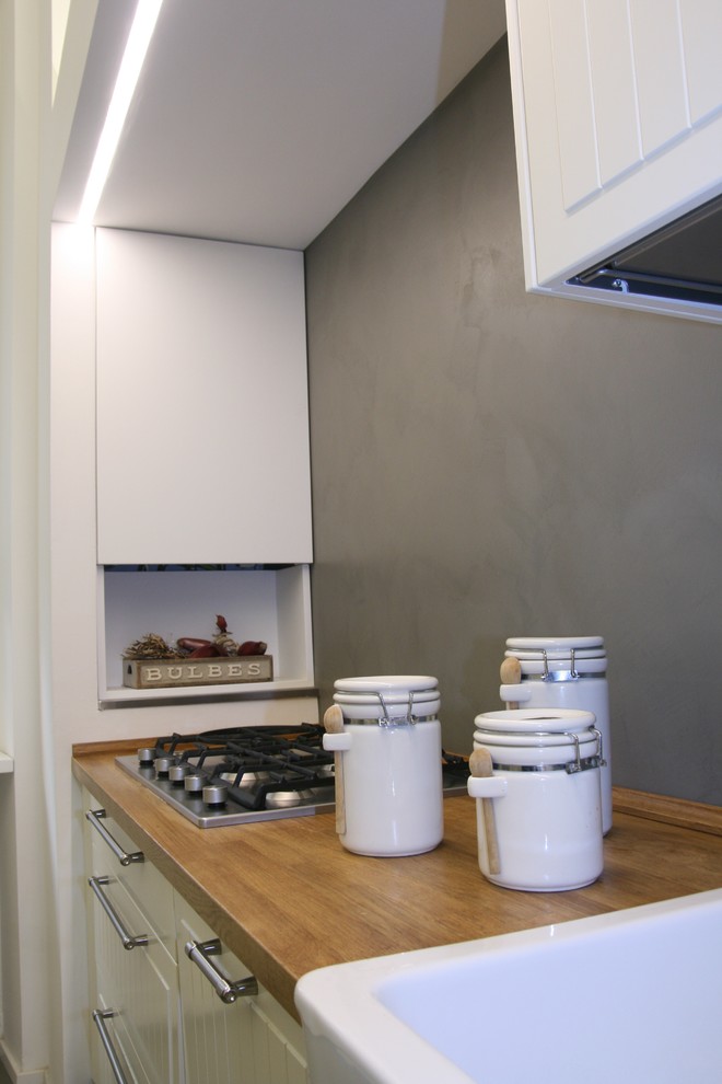 Idéer för ett mellanstort shabby chic-inspirerat kök, med en nedsänkt diskho, luckor med upphöjd panel, vita skåp, träbänkskiva, grått stänkskydd och betonggolv