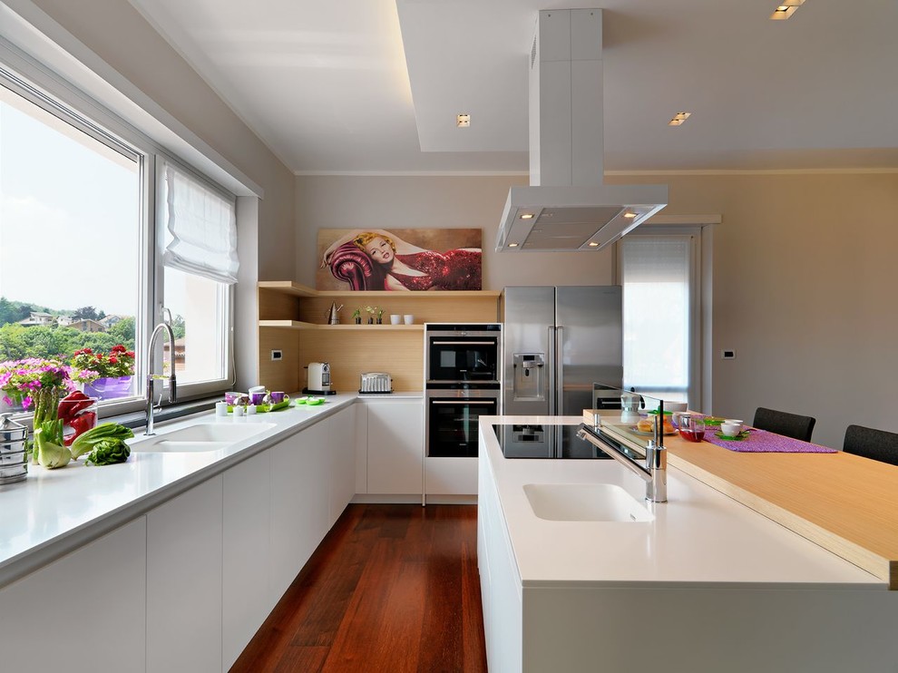 Immagine di una cucina contemporanea di medie dimensioni con lavello integrato, ante lisce, ante bianche, paraspruzzi con lastra di vetro, elettrodomestici in acciaio inossidabile e pavimento in legno massello medio