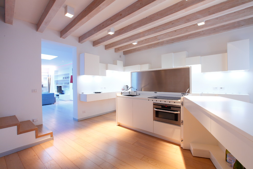 Cette image montre une grande cuisine ouverte avec un placard à porte plane, des portes de placard blanches, une crédence blanche, parquet clair et îlot.