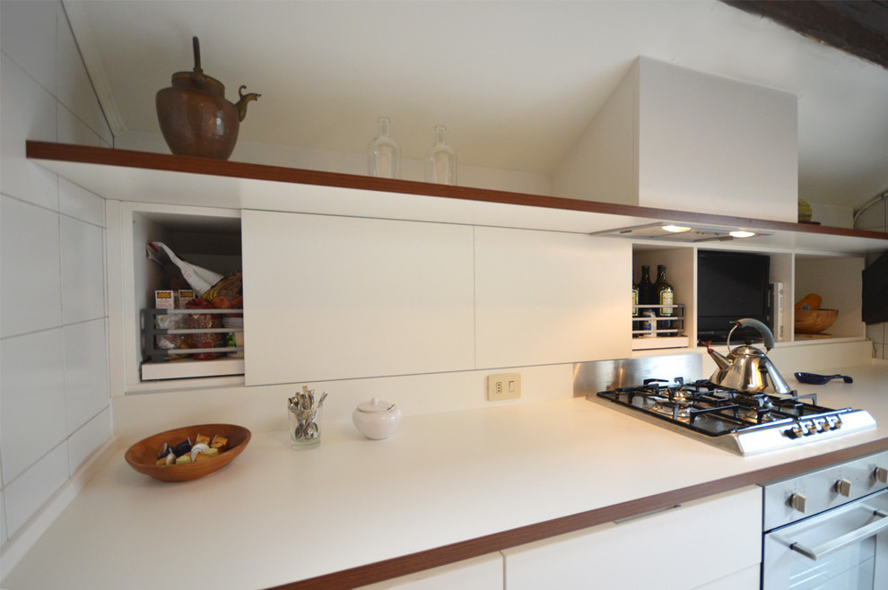 Landhausstil Küche mit flächenbündigen Schrankfronten, weißen Schränken, Laminat-Arbeitsplatte und Küchengeräten aus Edelstahl in Mailand
