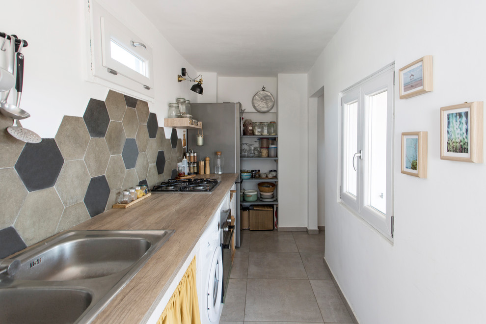 Small scandinavian single-wall enclosed kitchen in Naples with a double-bowl sink, open cabinets, white cabinets, wood worktops, multi-coloured splashback, cement tile splashback, stainless steel appliances, porcelain flooring, no island, grey floors and brown worktops.