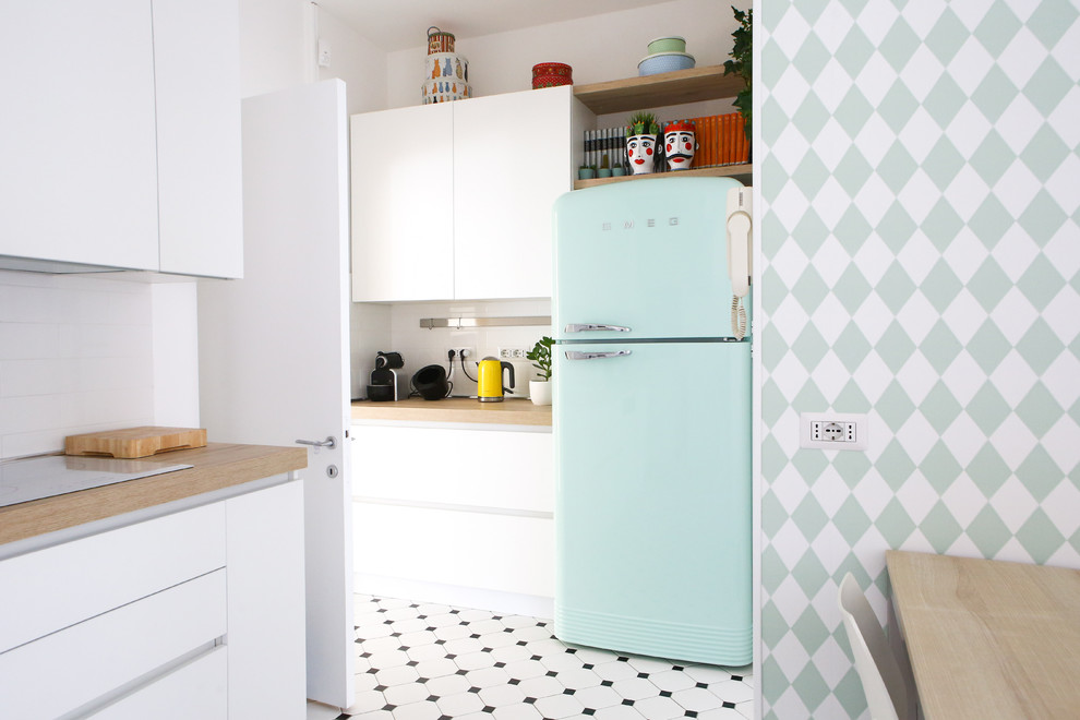 This is an example of an eclectic kitchen in Milan with flat-panel cabinets, white cabinets, wood worktops, white splashback, coloured appliances, multi-coloured floors and beige worktops.