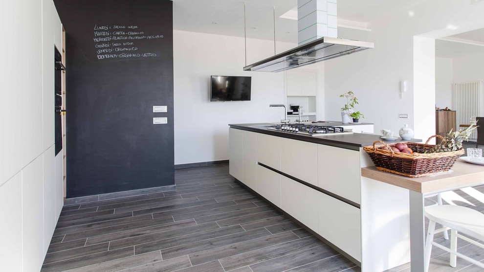 Bild på ett mellanstort funkis kök, med en integrerad diskho, släta luckor, rostfria vitvaror, laminatgolv, flera köksöar och grått golv