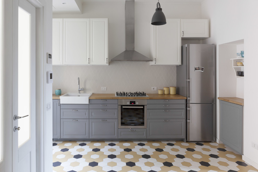 Bild på ett mellanstort skandinaviskt linjärt kök med öppen planlösning, med en enkel diskho, grå skåp, träbänkskiva, stänkskydd i keramik, rostfria vitvaror, klinkergolv i keramik, flerfärgat golv, luckor med upphöjd panel och grått stänkskydd