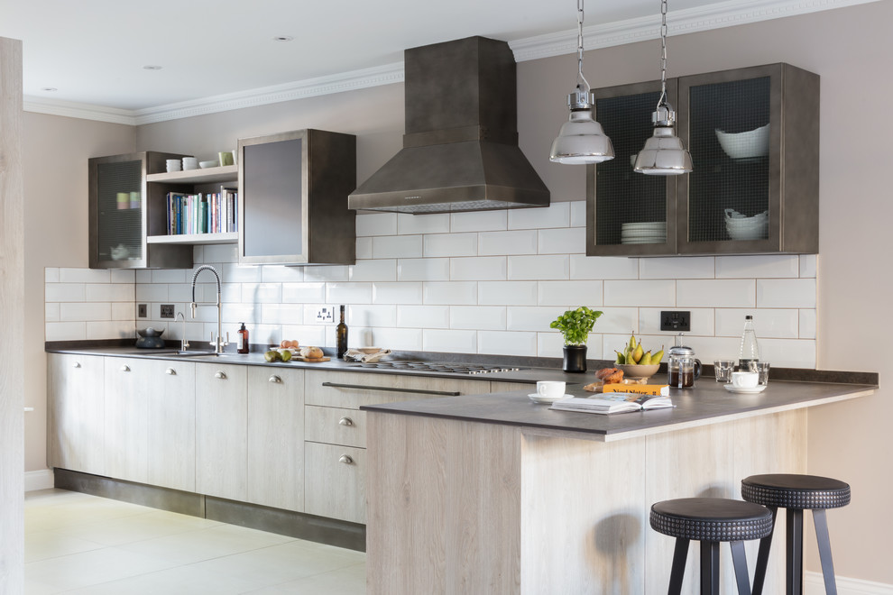 Einzeilige Moderne Küche mit flächenbündigen Schrankfronten, dunklen Holzschränken, Küchenrückwand in Weiß, Rückwand aus Metrofliesen, Keramikboden, Halbinsel und weißem Boden in London