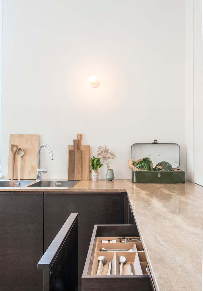 Cette image montre une cuisine design en bois brun avec plan de travail en marbre, une crédence blanche et un sol en bois brun.