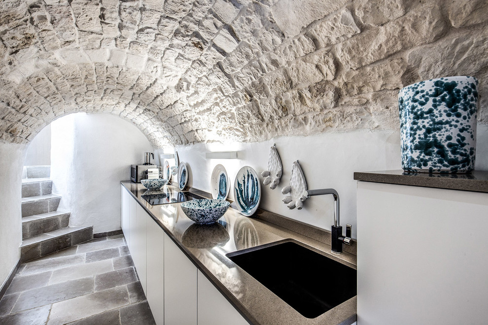 Idee per una cucina lineare mediterranea chiusa con lavello sottopiano, ante lisce, ante bianche, nessuna isola, pavimento grigio e top grigio