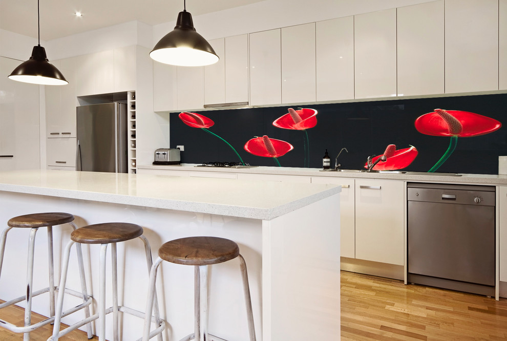 Cette image montre une cuisine américaine design de taille moyenne avec un plan de travail en verre et une crédence en feuille de verre.