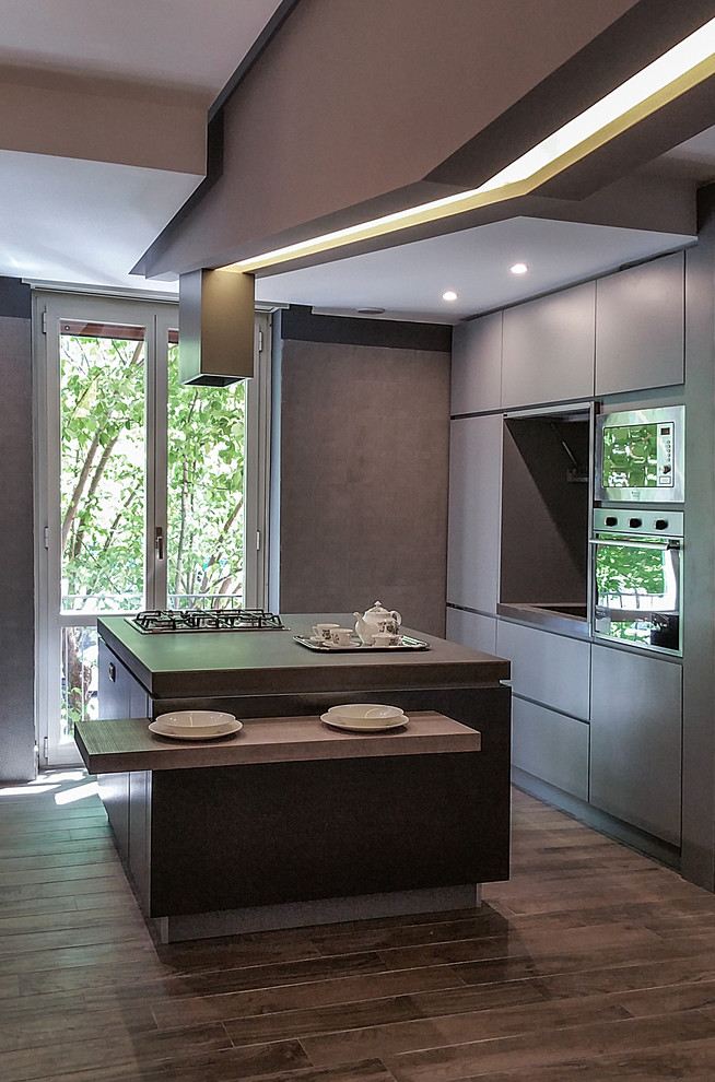 This is an example of a medium sized urban single-wall kitchen/diner in Rome with flat-panel cabinets, grey cabinets, stainless steel worktops, grey splashback and an island.
