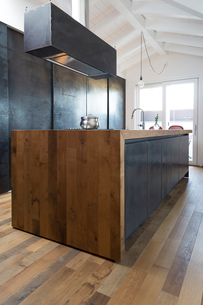 Modelo de cocina lineal actual grande abierta con armarios con paneles lisos, puertas de armario negras, encimera de madera, suelo de madera en tonos medios y una isla