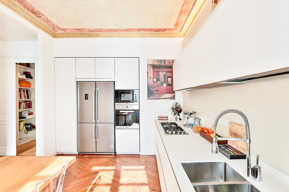 Inspiration för stora moderna linjära kök med öppen planlösning, med en dubbel diskho, släta luckor, vita skåp, beige stänkskydd, mellanmörkt trägolv och brunt golv
