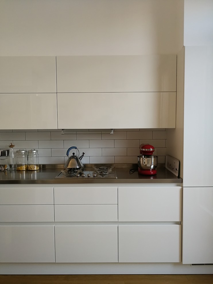 Mittelgroße Moderne Küche mit Kassettenfronten, weißen Schränken und Edelstahl-Arbeitsplatte