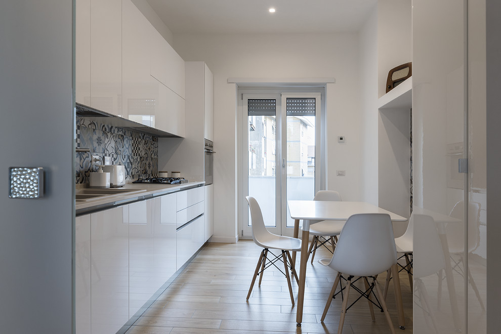 Trendy single-wall light wood floor and beige floor enclosed kitchen photo in Rome with a double-bowl sink, flat-panel cabinets, white cabinets, multicolored backsplash, stainless steel appliances, no island and white countertops