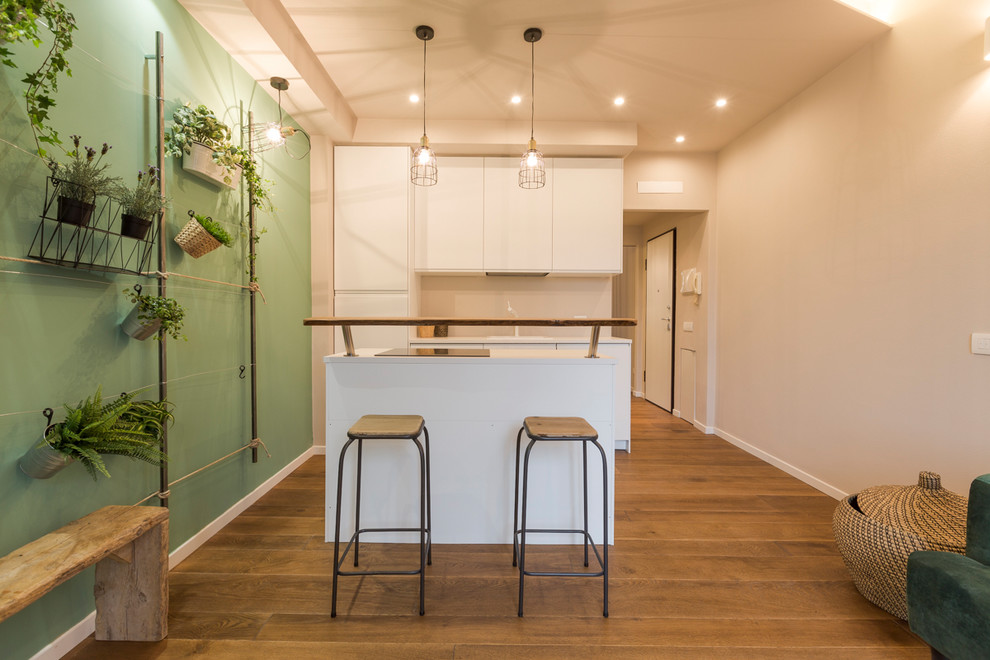 Idée de décoration pour une cuisine ouverte parallèle design de taille moyenne avec un sol marron, des portes de placard blanches, une crédence blanche, un placard à porte plane, un sol en bois brun et îlot.