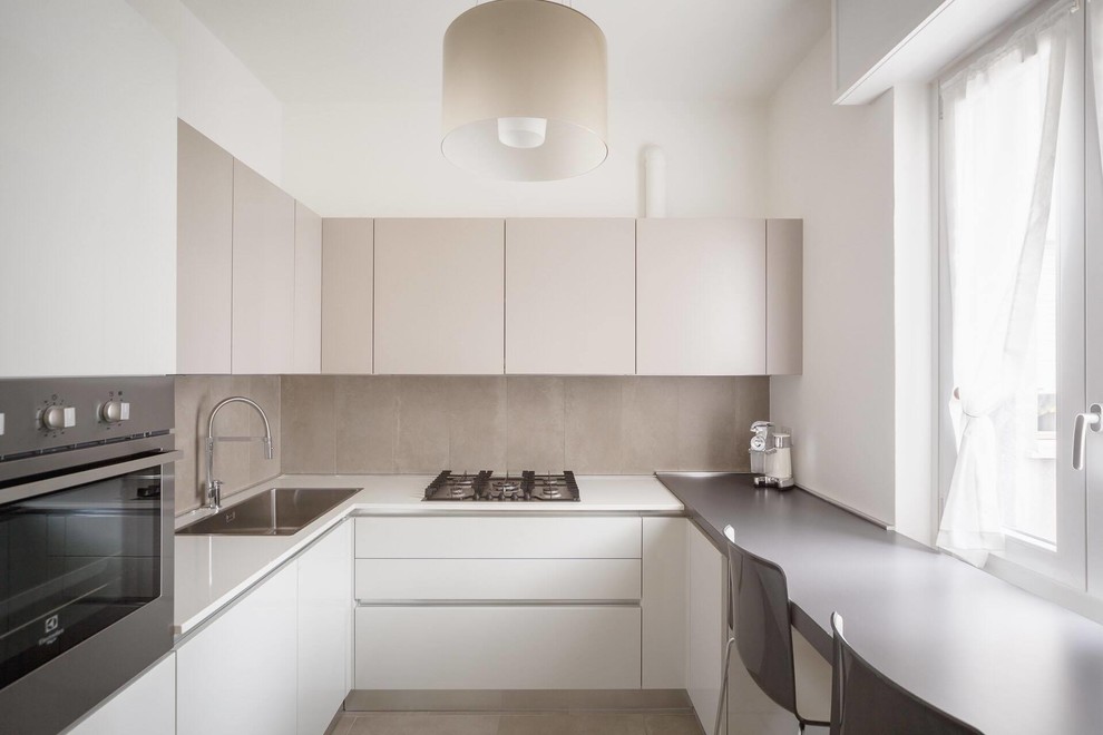 Kleine Moderne Wohnküche in U-Form mit Einbauwaschbecken, flächenbündigen Schrankfronten, Küchenrückwand in Beige und Küchengeräten aus Edelstahl in Mailand
