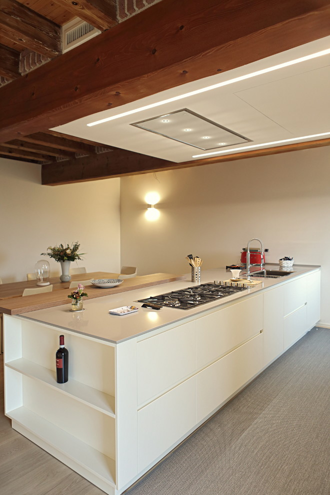 Example of a mid-sized minimalist laminate floor and gray floor eat-in kitchen design in Venice with a single-bowl sink, flat-panel cabinets, solid surface countertops and a peninsula