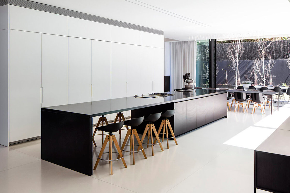 Ejemplo de cocina comedor alargada moderna extra grande con fregadero bajoencimera, armarios con paneles lisos, una isla y con blanco y negro