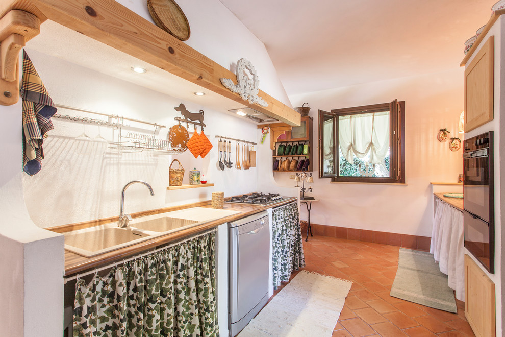 Bild på ett avskilt medelhavsstil beige linjärt beige kök, med rostfria vitvaror, en nedsänkt diskho, luckor med infälld panel, skåp i ljust trä, träbänkskiva, vitt stänkskydd, tegelgolv och brunt golv
