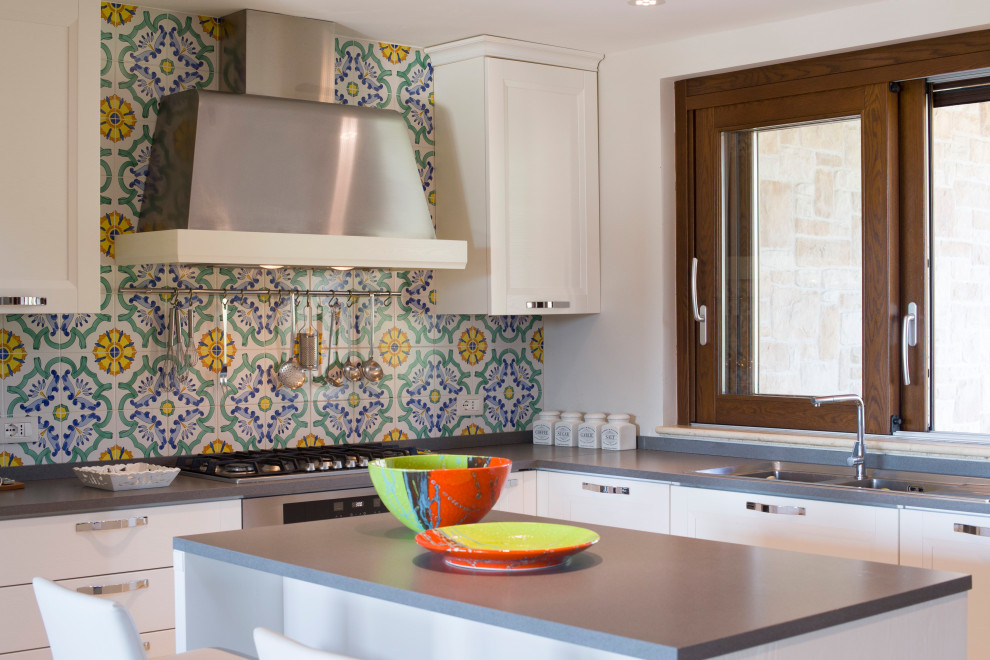 Modern inredning av ett litet grå grått l-kök, med en dubbel diskho, släta luckor, vita skåp, flerfärgad stänkskydd, stänkskydd i mosaik, rostfria vitvaror och en köksö