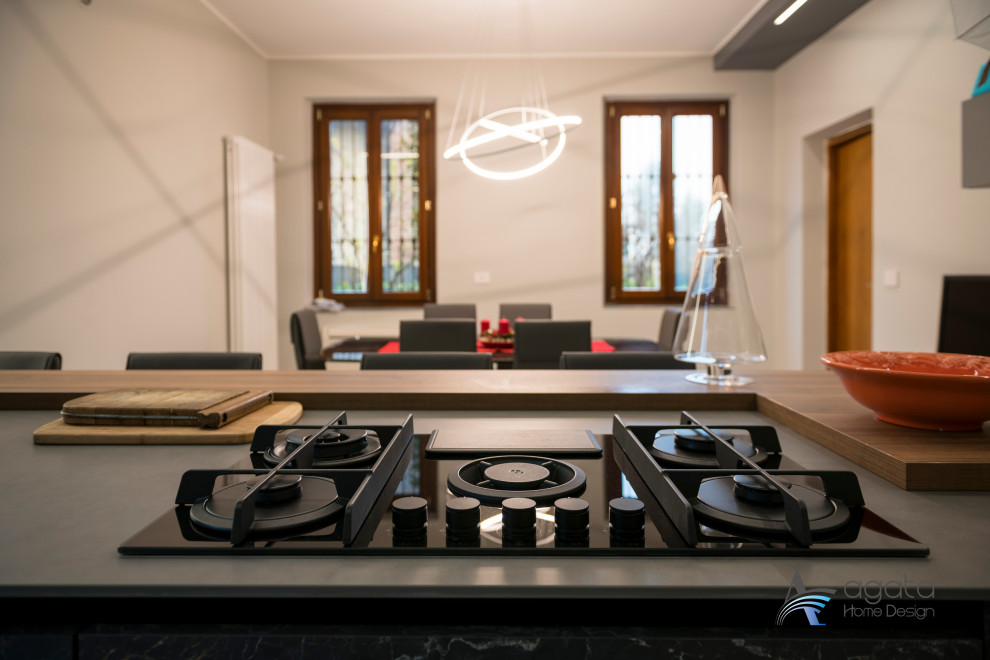 Свежая идея для дизайна: параллельная кухня среднего размера в стиле модернизм с обеденным столом, двойной мойкой, черной техникой, полом из керамогранита, островом и серым полом - отличное фото интерьера