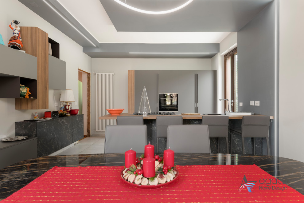 Medium sized modern galley kitchen/diner in Turin with a double-bowl sink, black appliances, porcelain flooring, an island and grey floors.