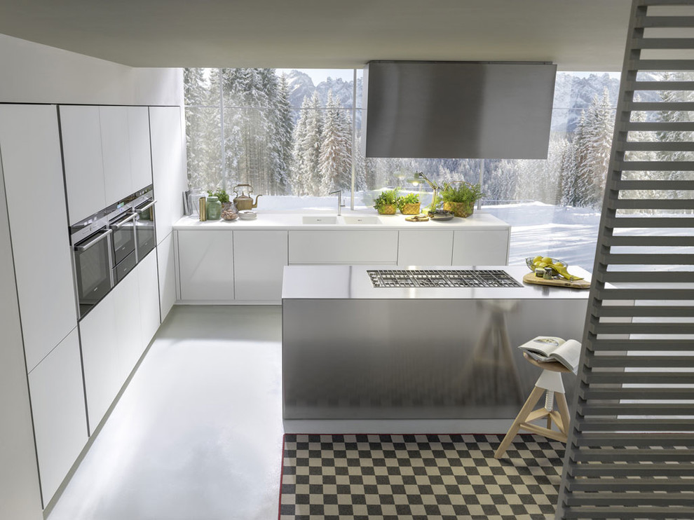 Immagine di una grande cucina design con lavello a doppia vasca, ante di vetro, ante bianche, top in superficie solida, paraspruzzi bianco, paraspruzzi in ardesia, elettrodomestici in acciaio inossidabile e pavimento in cemento