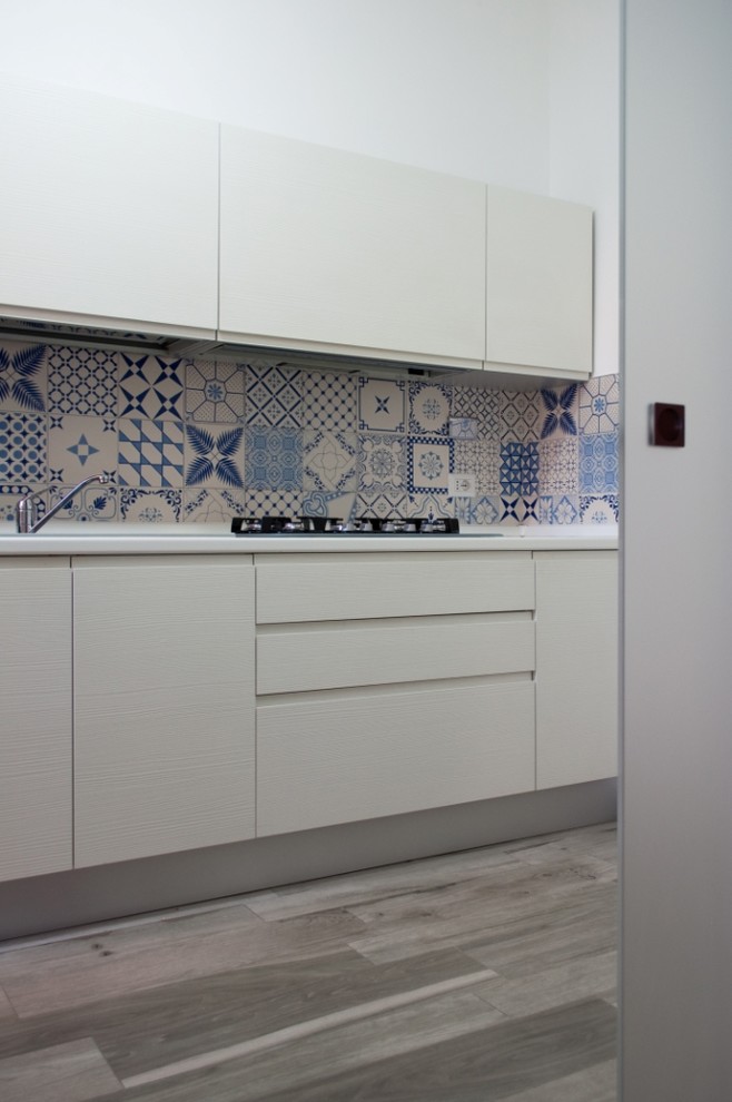 Inspiration for a medium sized modern single-wall enclosed kitchen in Rome with a built-in sink, flat-panel cabinets, white cabinets, blue splashback, ceramic splashback and porcelain flooring.