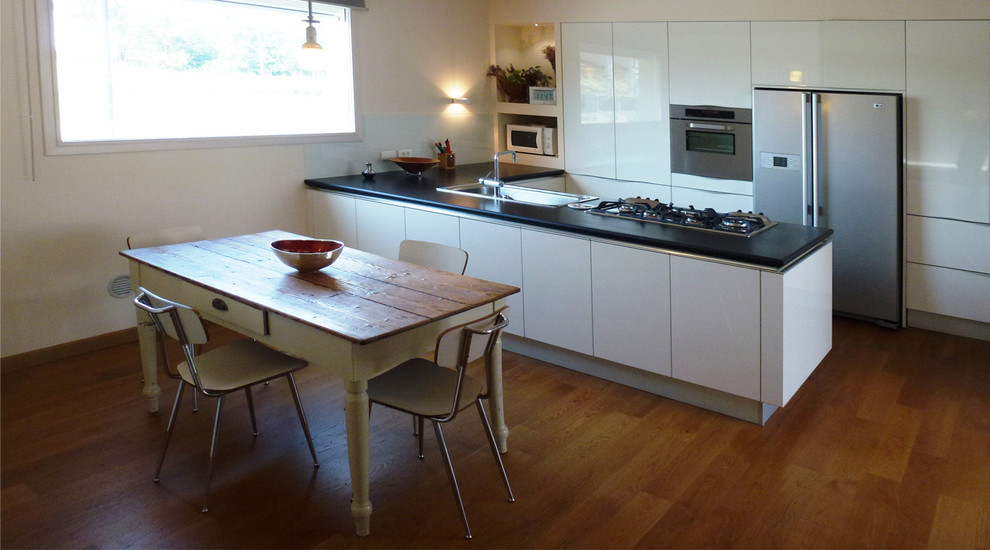 Ispirazione per una grande cucina minimal con ante lisce, ante in legno chiaro, pavimento in legno massello medio e pavimento marrone