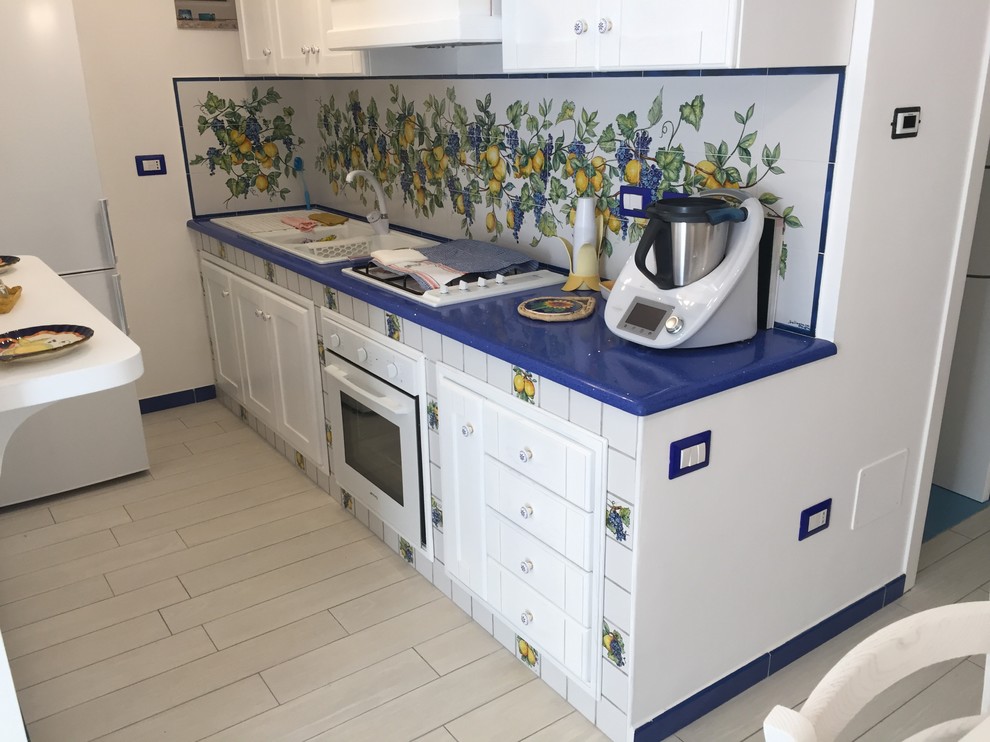 Diseño de cocina mediterránea pequeña sin isla con fregadero de doble seno, puertas de armario blancas, electrodomésticos blancos y suelo de baldosas de porcelana