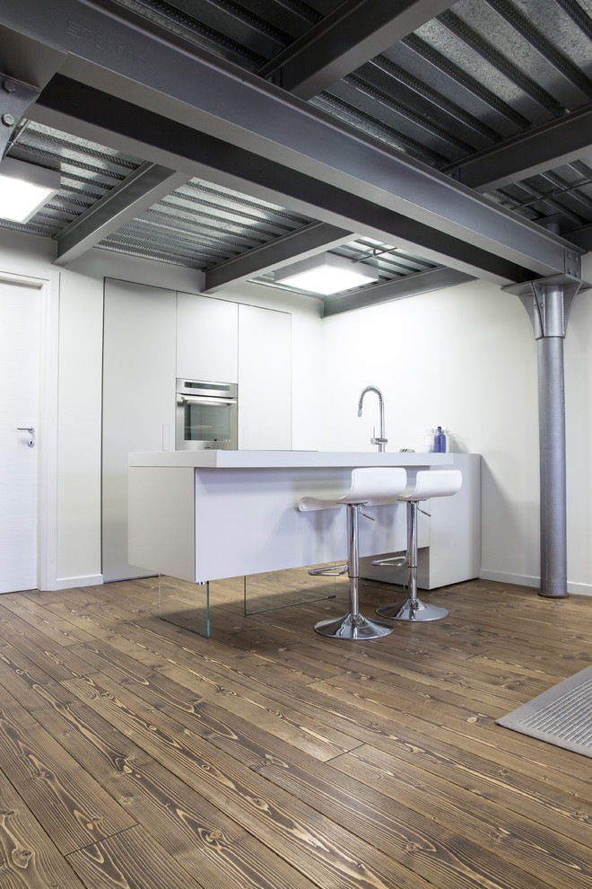 Esempio di una cucina industriale di medie dimensioni con lavello a vasca singola, ante bianche, top in laminato, elettrodomestici in acciaio inossidabile, parquet scuro e pavimento marrone