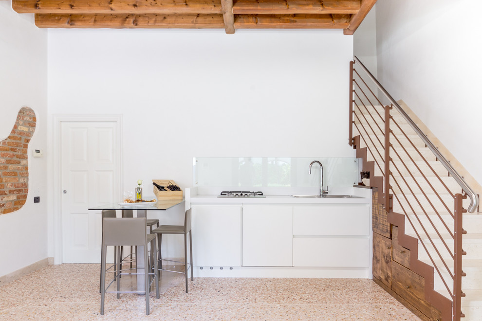 Diseño de cocina minimalista con fregadero encastrado, armarios con paneles lisos, puertas de armario blancas y salpicadero de vidrio templado