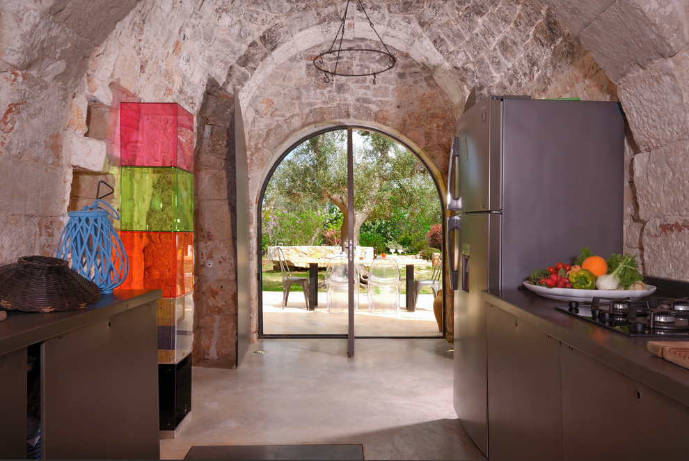 Zweizeilige, Mittelgroße Mediterrane Küche mit Betonboden, grauem Boden, flächenbündigen Schrankfronten, Edelstahlfronten und Küchenrückwand in Beige in Sonstige